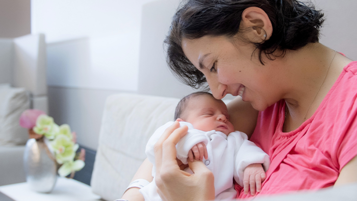 Schwangere Frau hält liebevoll ihr Baby und lächelt
